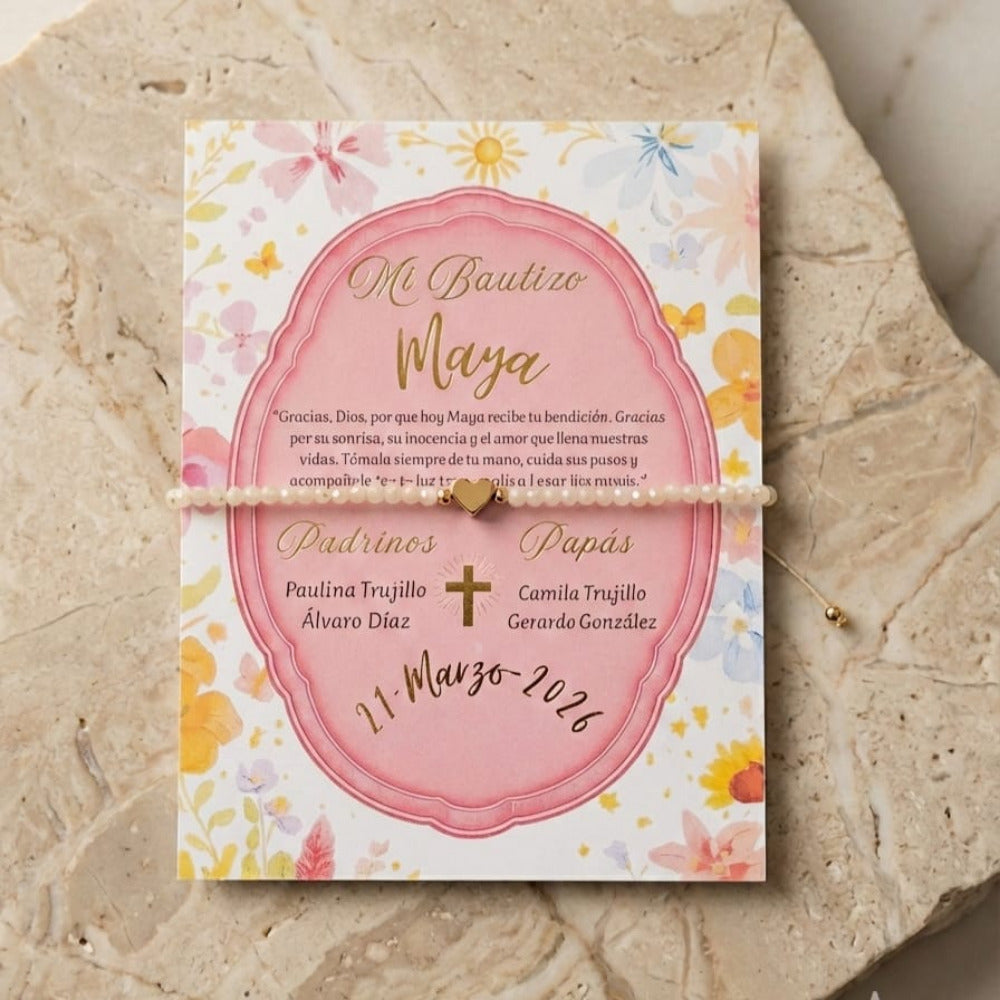 Pulsera de cuentas con dije de corazón dorado, presentada en tarjeta personalizada con diseño floral rosa, ideal como recuerdo para bautizo.