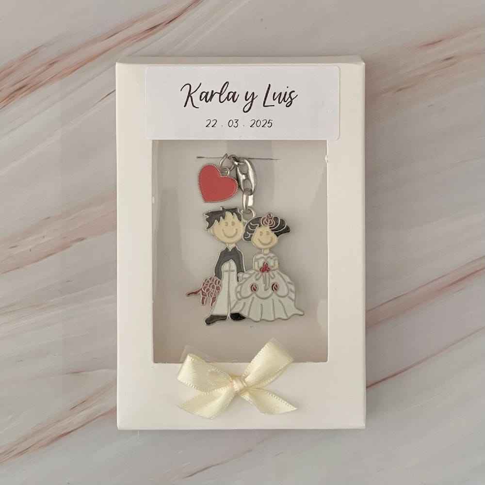 Recuerdo de boda personalizado: Llavero de novios en caricatura con corazón, presentado en caja de regalo blanca con moño y etiqueta.