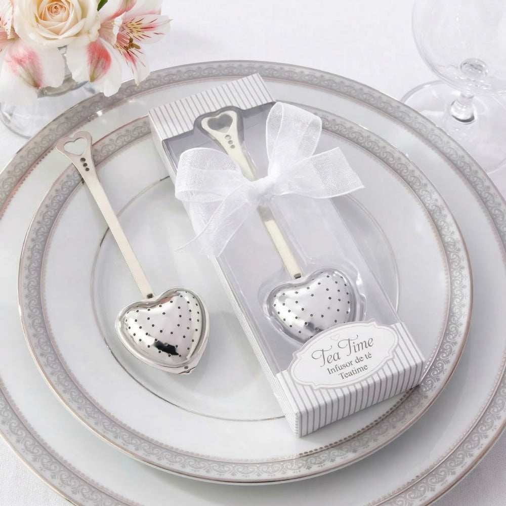 Infusor de té metálico en forma de corazón, presentado en estuche de regalo con moño, ideal como recuerdo para eventos.