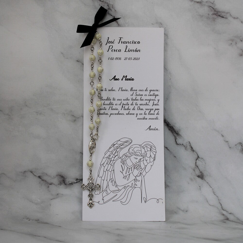 Decenario blanco con cruces sobre una tarjeta con la oración de la virgen maria.