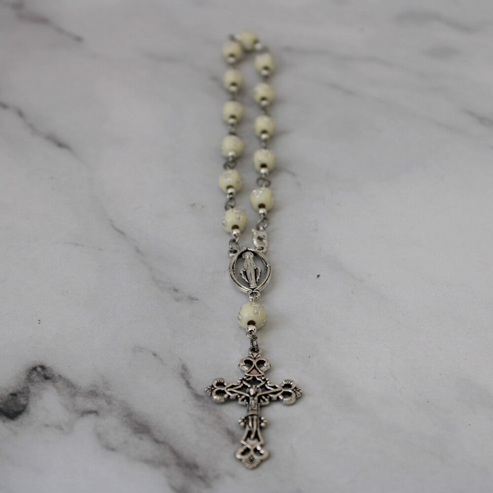 Decenario con cuentas  blancas con cruces y una cruz plateada.