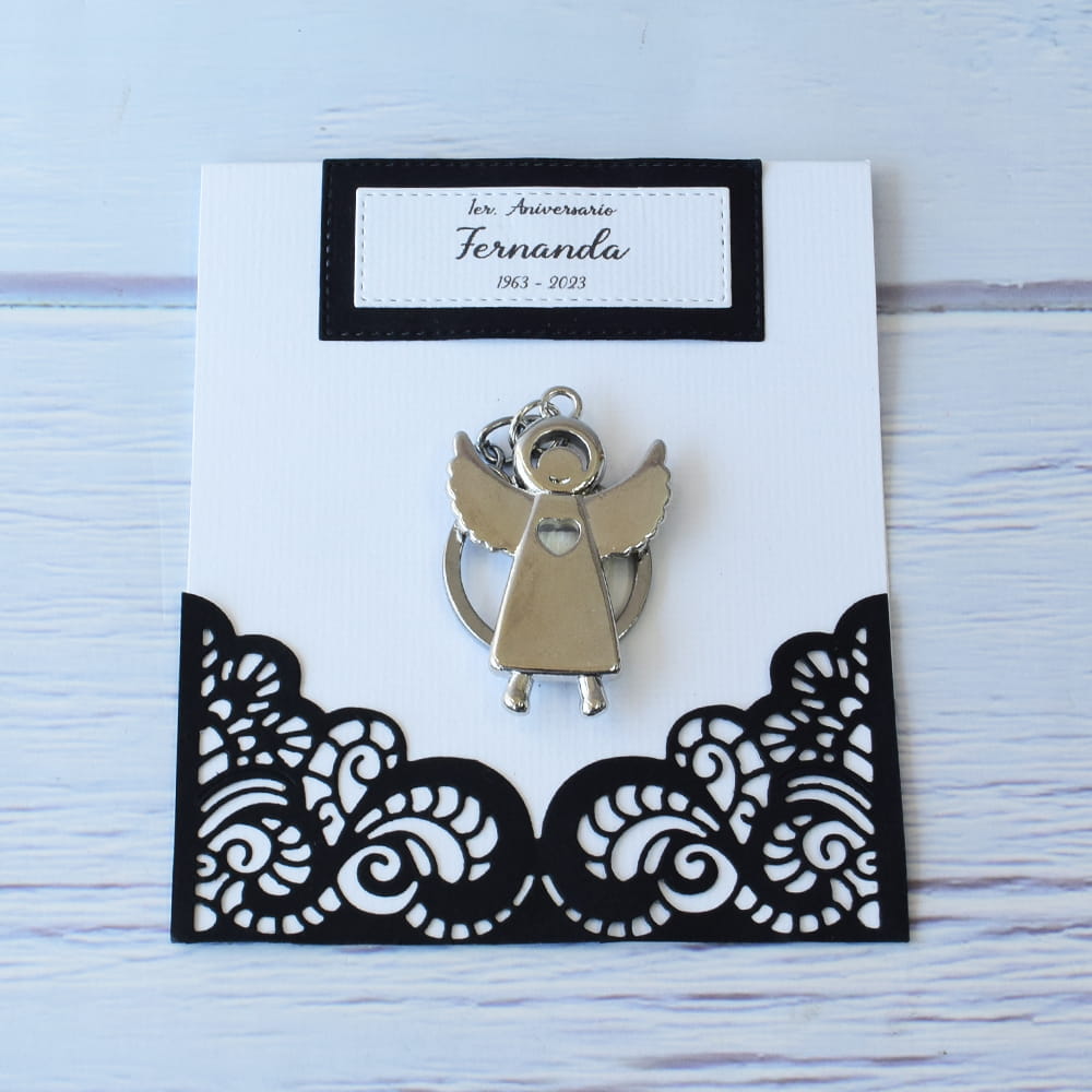 Recuerdo para aniversario luctuoso. Elegante tarjeta blanca y negra con corte láser personalizado, que incluye un llavero metálico de ángel de la guarda plateado, ideal para agradecer a los acompañantes en ceremonias conmemorativas.