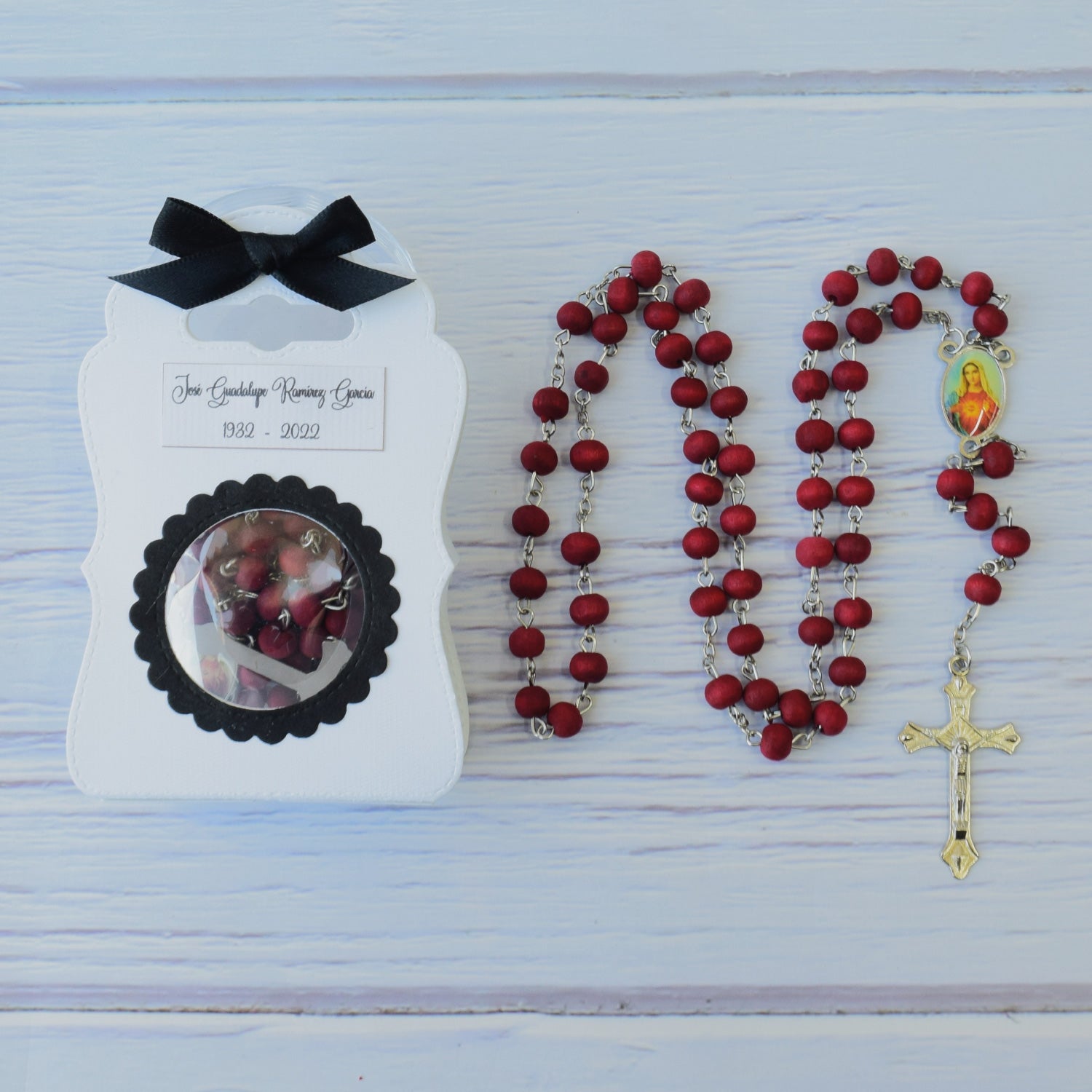 Rosario de madera de palo de rosa con cuentas rojas y crucifijo plateado, ideal como recuerdo para eventos luctuosos.