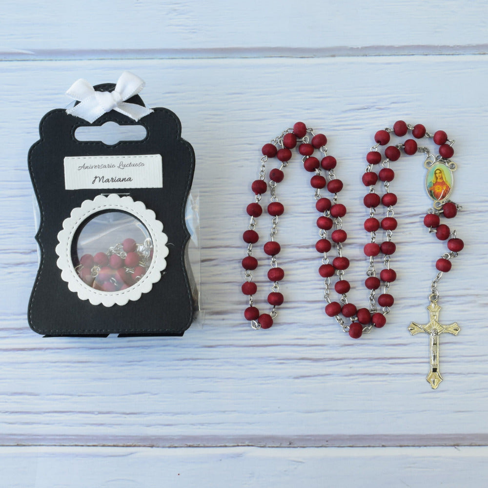Recuerdo para aniversario luctuoso: rosario de madera roja con cruz plateada en cajita negra personalizada.