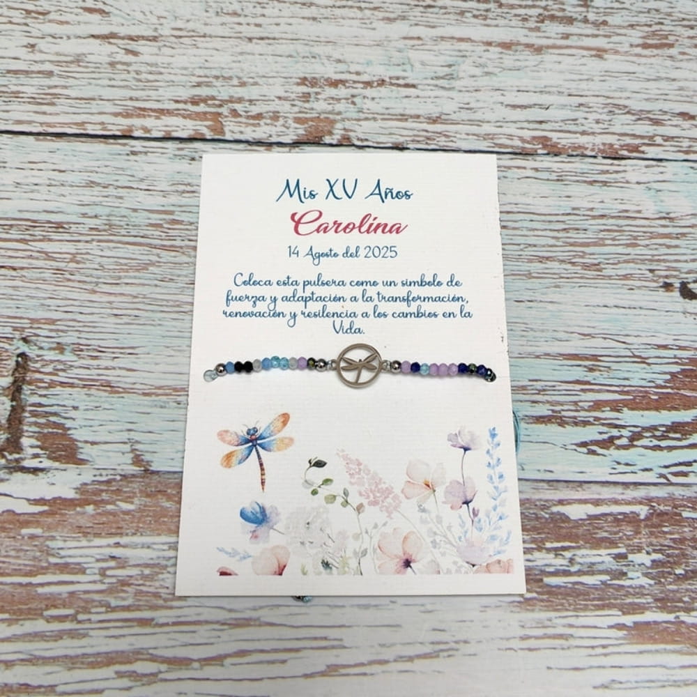 Pulsera con dije de libélula sobre tarjeta personalizable de recuerdo para XV años con flores de acuarela.