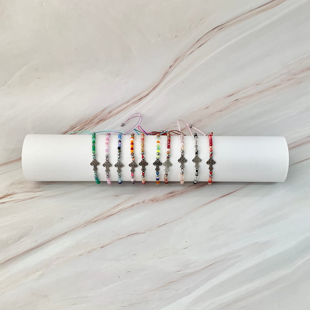 Recuerdos religiosos de pulseras ajustables de colores con dije de cruz metálica plateada.
