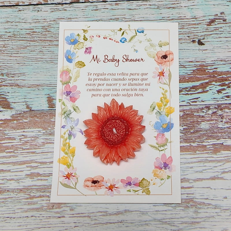 Vela artesanal en forma de flor sobre tarjeta personalizada, ideal como recuerdo de baby shower con diseño floral decorativo.