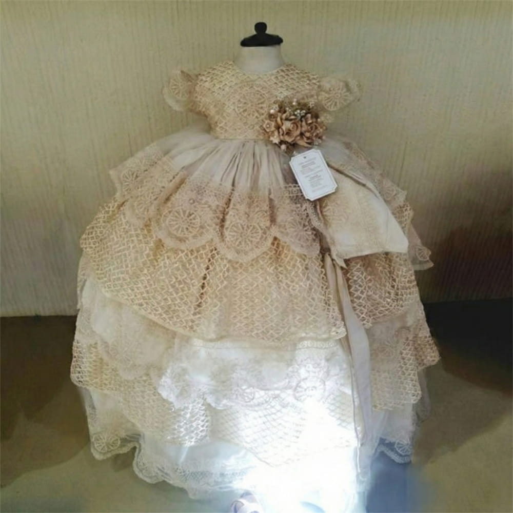 Ropón de bautizo para niña con diseño de encaje en capas, detalles artesanales y flor decorativa en la cintura, ideal para ceremonias religiosas.